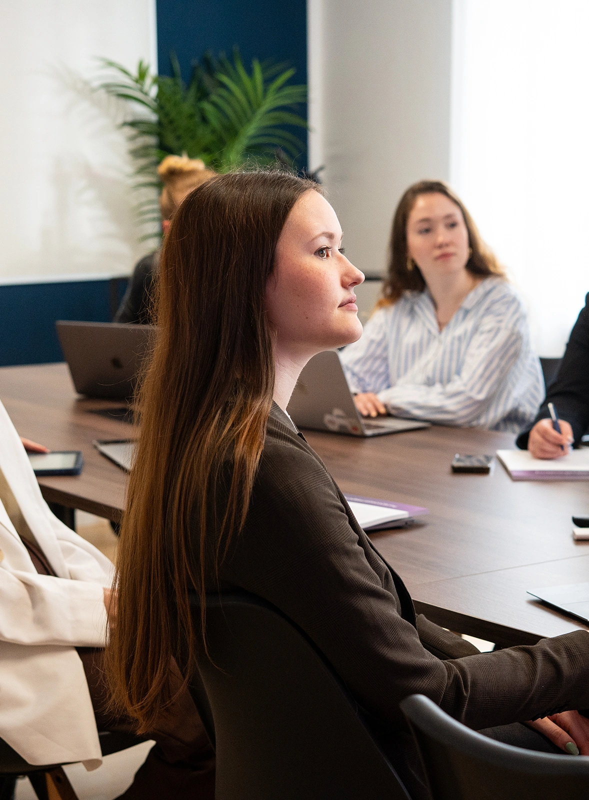 Mehrere Mitarbeiterinnen sitzen an einem Konferenztisch und schauen in eine Richtung.