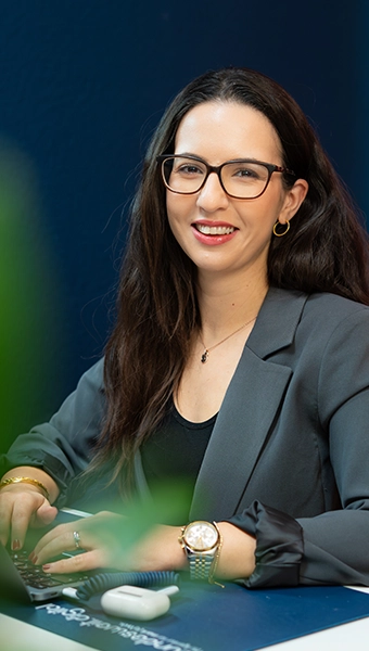 Merve sitzt am Arbeitsplatz und lächelt in die Kamera.